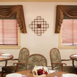 A neatly arranged dining room featuring ornate curtains, decorative wall art, and elegantly set tables.