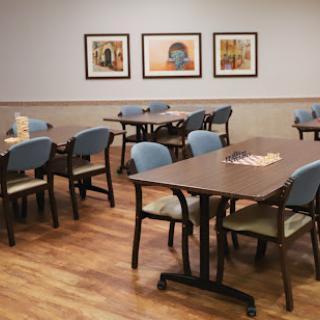 A casual dining area featuring neatly arranged tables and chairs, adorned with artworks on the walls.