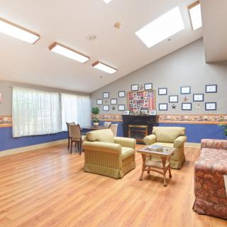 A cozy living room featuring comfortable seating, a fireplace, and natural lighting from skylights.