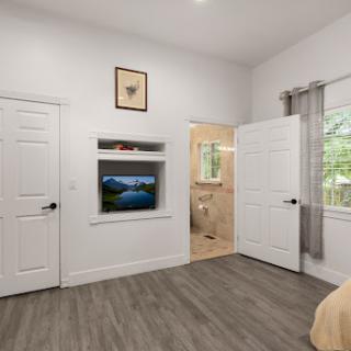 A cozy bedroom featuring modern decor, large windows for natural light, and a mounted television.