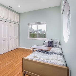 A minimalist bedroom featuring a single bed, large closet, and hardwood flooring.