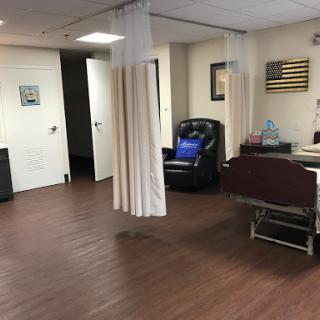A view of a patient room in a medical facility, featuring curtains for privacy and various furniture.