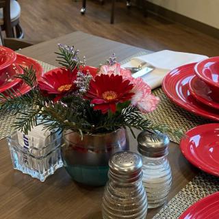 A dining table set with red plates and a floral centerpiece.