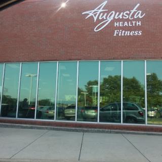 The exterior of Augusta Health Fitness featuring large windows and a brick facade.