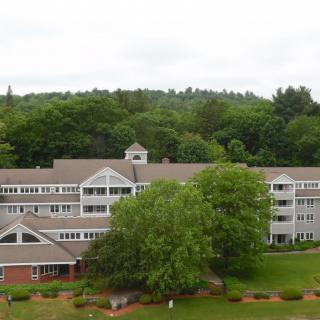 A large multi-story building nestled among lush trees and greenery.