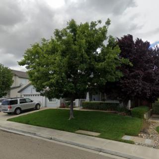 A suburban house with a well-maintained lawn and trees on a cloudy day.
