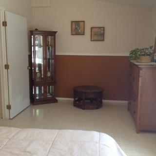 A cozy bedroom with a wooden cabinet, decorative items, and a potted plant.
