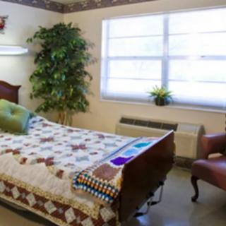 A cozy bedroom setup with a single bed, a comfortable chair, and a large window allowing natural light.