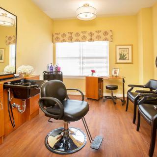 A cozy and well-lit hair salon interior with seating and styling stations.