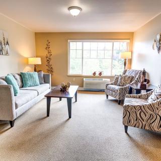 A cozy living room with a sofa, patterned chairs, and a large window letting in natural light.