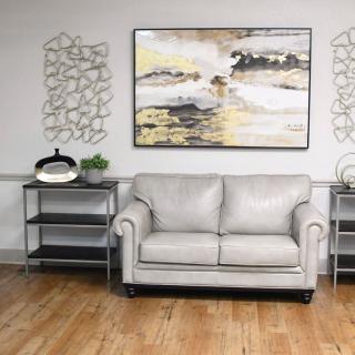 A modern living room with a gray sofa, abstract artwork, and decorative shelves on either side.