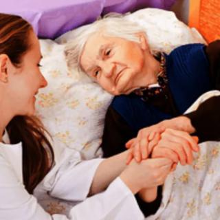 A nurse provides compassionate care to an elderly patient in a hospital bed.