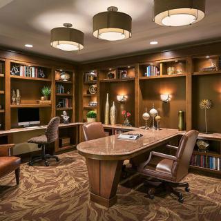 A well-designed office space with built-in bookshelves, comfortable seating, and warm lighting.