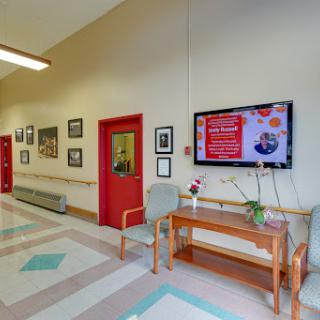 A spacious hallway featuring a television screen, decorative plants, and framed photographs on the walls.