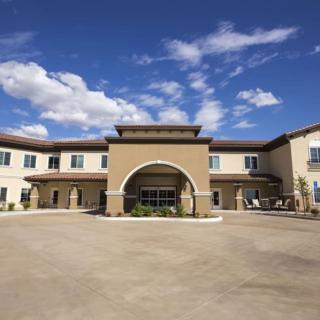 A two-story building with a grand entrance under a sunny sky with scattered clouds.
