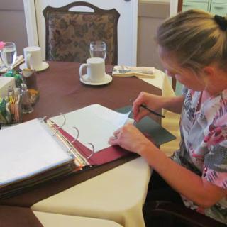 A woman reviews documents in a binder at a table.