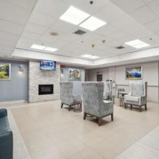 A modern waiting room with comfortable seating, a television, and a fireplace.