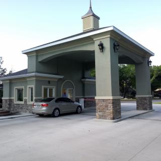 A car at a drive-thru building with a covered structure.
