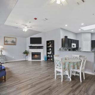 A modern open-concept living space featuring hardwood floors, a fireplace, and a dining area adjacent to the kitchen.