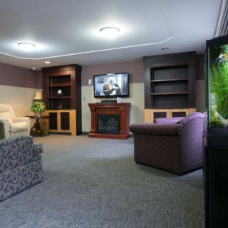 A cozy living room with a television, fireplace, sofas, and bookshelves.