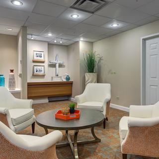 A cozy waiting room featuring elegant chairs around a central table with decorative elements.
