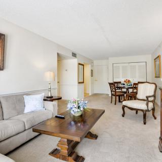 A cozy living room with a sofa and wooden furniture leading to a dining area.