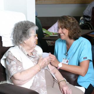 A healthcare professional interacts warmly with an elderly woman.