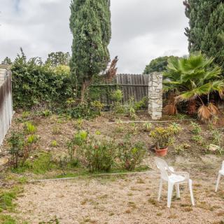 A backyard garden with plastic chairs, trees, and a wooden fence.