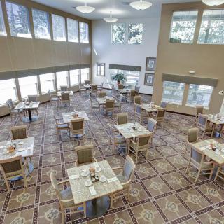 A spacious dining area with neatly arranged tables and chairs, featuring large windows that allow natural light to fill the room.