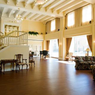A spacious, elegantly decorated living room with large windows and a wooden floor.