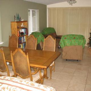 A dining and living area featuring a wooden table with chairs, a bookshelf, and comfortable seating.