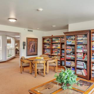 A cozy library reading area with bookshelves, a table, and chairs.