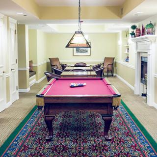 A cozy game room featuring a pool table, elegant lighting, and a fireplace.