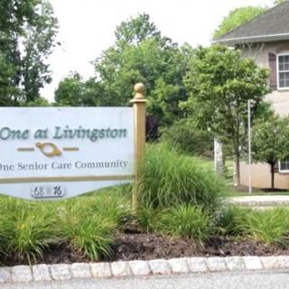 Entrance sign for a private adult community surrounded by greenery.