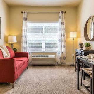 A cozy living room with a red sofa and patterned curtains, featuring a large window and stylish decor.