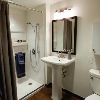 A modern bathroom featuring a shower, sink, and toilet.