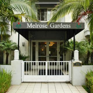 The entrance to Melrose Gardens features a welcoming awning and tropical landscaping.
