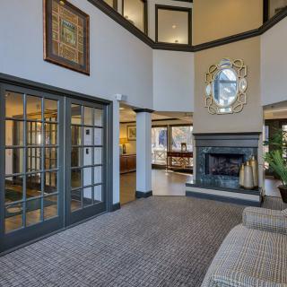 A modern two-story living room featuring a central fireplace, large windows, and elegant interior design.