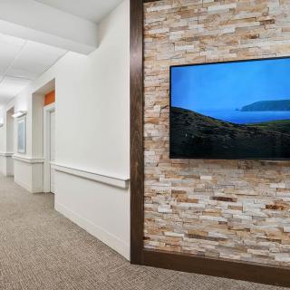 A modern hallway featuring a mounted television on a stylish stone accent wall.