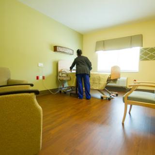 A nurse attends to medical equipment in a patient room, characterized by a calm and clean interior.
