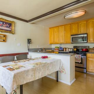 A cozy kitchen and dining area featuring wooden cabinets, stainless steel appliances, and a table with a cloth.