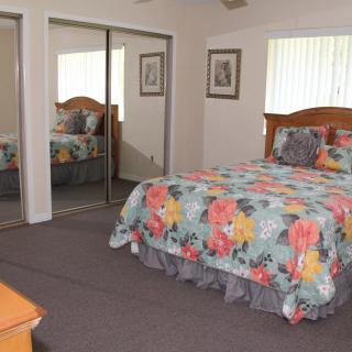 A cozy bedroom featuring a bed with colorful floral bedding, mirrored closet doors, and carpeted flooring.
