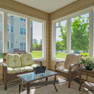 A bright sunroom with comfortable seating and large windows letting in natural light.