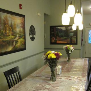 A cozy dining room with a decorated table, featuring fresh flower arrangements and illuminated by pendant lights.