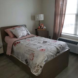 A cozy bedroom with a single bed and bedside lamp.