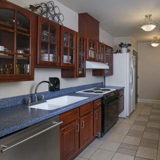 A modern kitchen with wooden cabinets, a dark countertop, and tiled flooring.