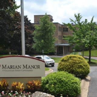 A scenic view of a building with surrounding greenery and a sign reading 'Marian Manor'.