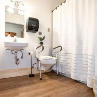 An accessible bathroom equipped with a toilet safety frame and a wall-mounted sink.