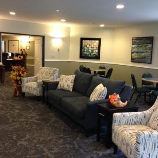 A cozy living room with sofas, chairs, and artwork on the walls.