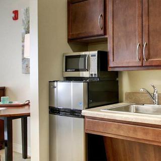 A compact kitchen area featuring a microwave, sink, and wooden cabinets.